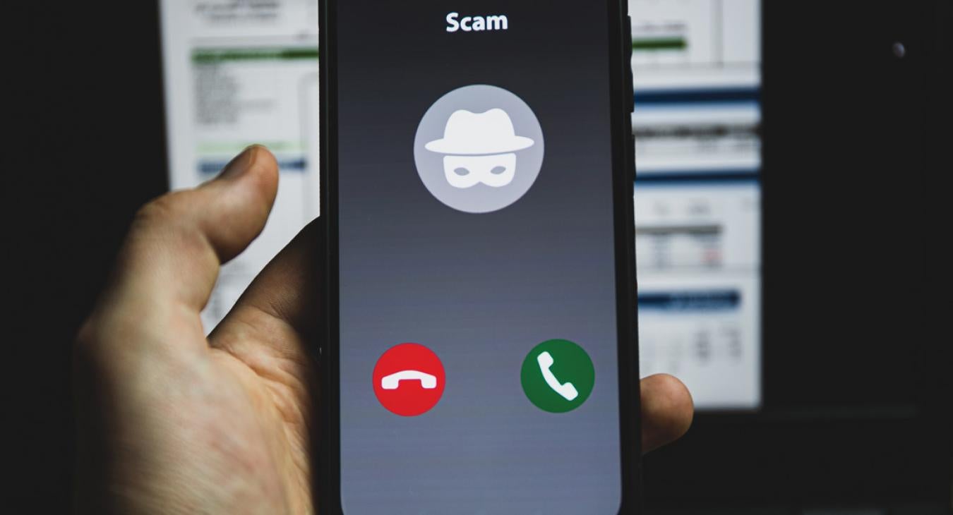 Hand holding cell phone with scam caller on screen