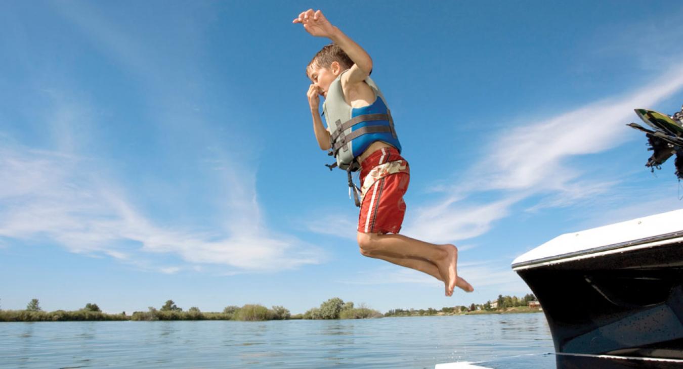 Little boy jumping into a lake