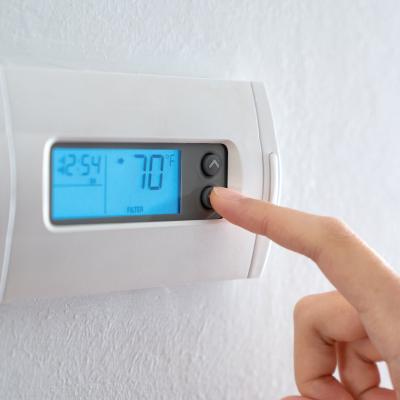 Woman adjusting temperature on a digital thermostat